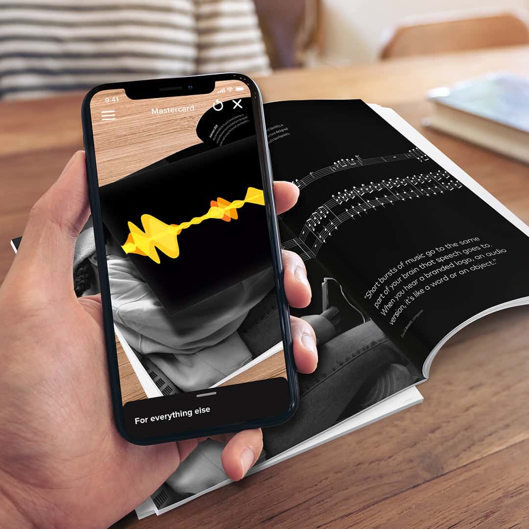 Phone scanning a magazine with AR overlays.