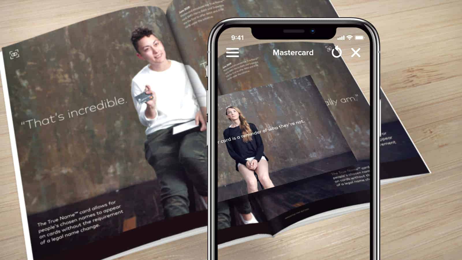 A smartphone scanning a Mastercard magazine showing addition digital information.