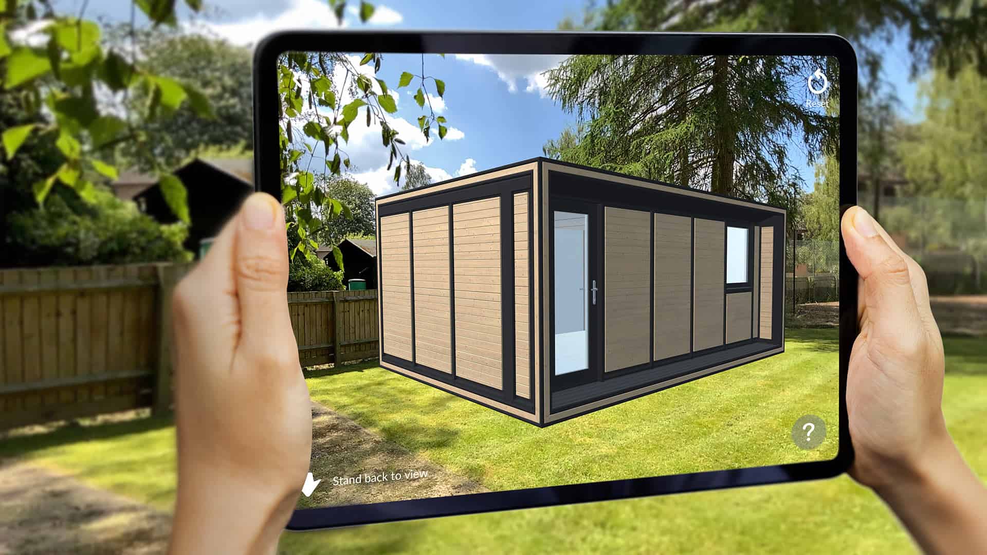 A person holding up a tablet device viewing an AR garden room in their garden.