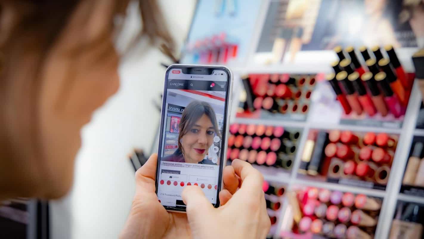 A person using their mobile phone camera to view makeup through augmented reality.