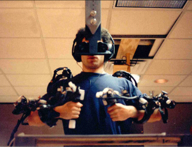 A man wearing an AR exoskeleton on his arms and binoculars to control 'virtual fixtures'. 