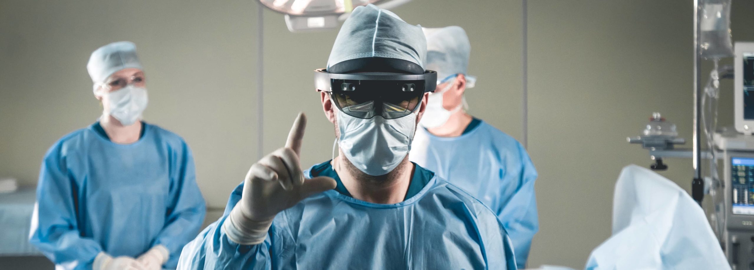 A surgeon wearing PPE and a HoloLens 2 headset in an operating theatre.