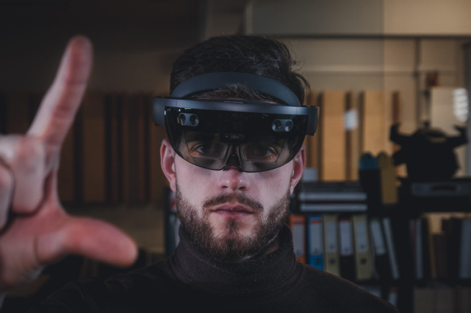 A man wearing the Microsoft hololens 2 controlling digital information with his hand.